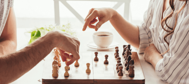 Close up view of the hands of a man and a woman playing chess